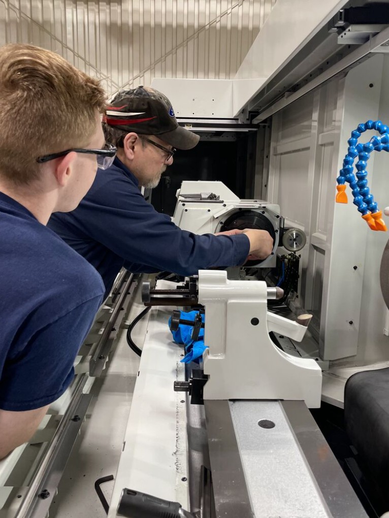 Two HFW machinists working together on CNC equipment