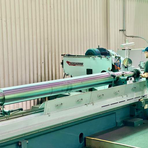 Precision cylindrical grinding of a large compressor shaft at HFW Industries.