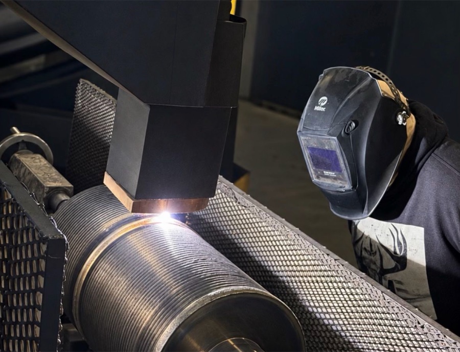 Operator monitoring a controlled hardfacing weld overlay on a large industrial component at HFW Industries
